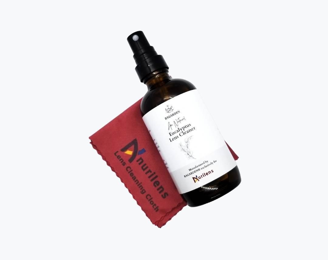 Brown 4 ounce glass bottle of Au Naturel Eucalyptus Lens Cleaner lying on a red lens cleaning cloth by NURILENS.