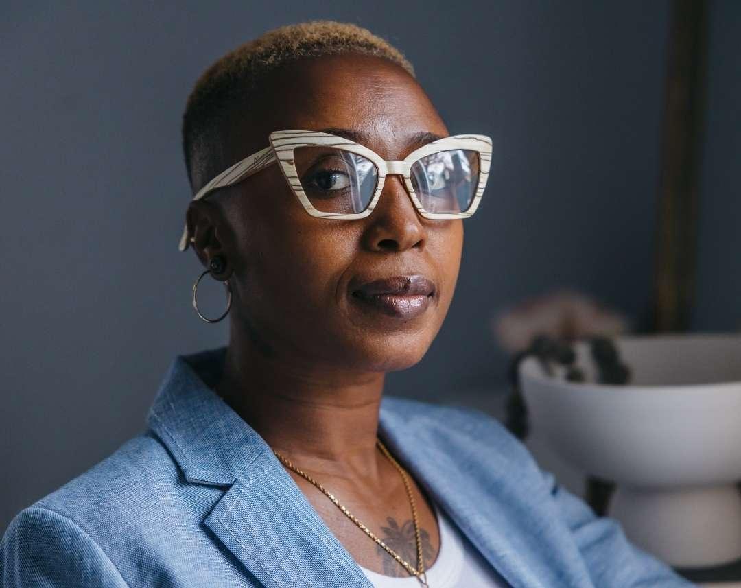 Black woman wearing beige cat eye wooden eyeglasses made of ice wood with black striped wood grain accents by NURILENS.