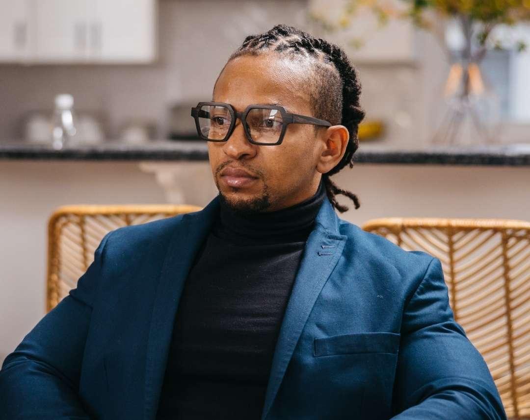 Black man in a blue suit wearing dark brown wayframe eyeglasses made of ebony with subtle black wood grain by NURILENS.