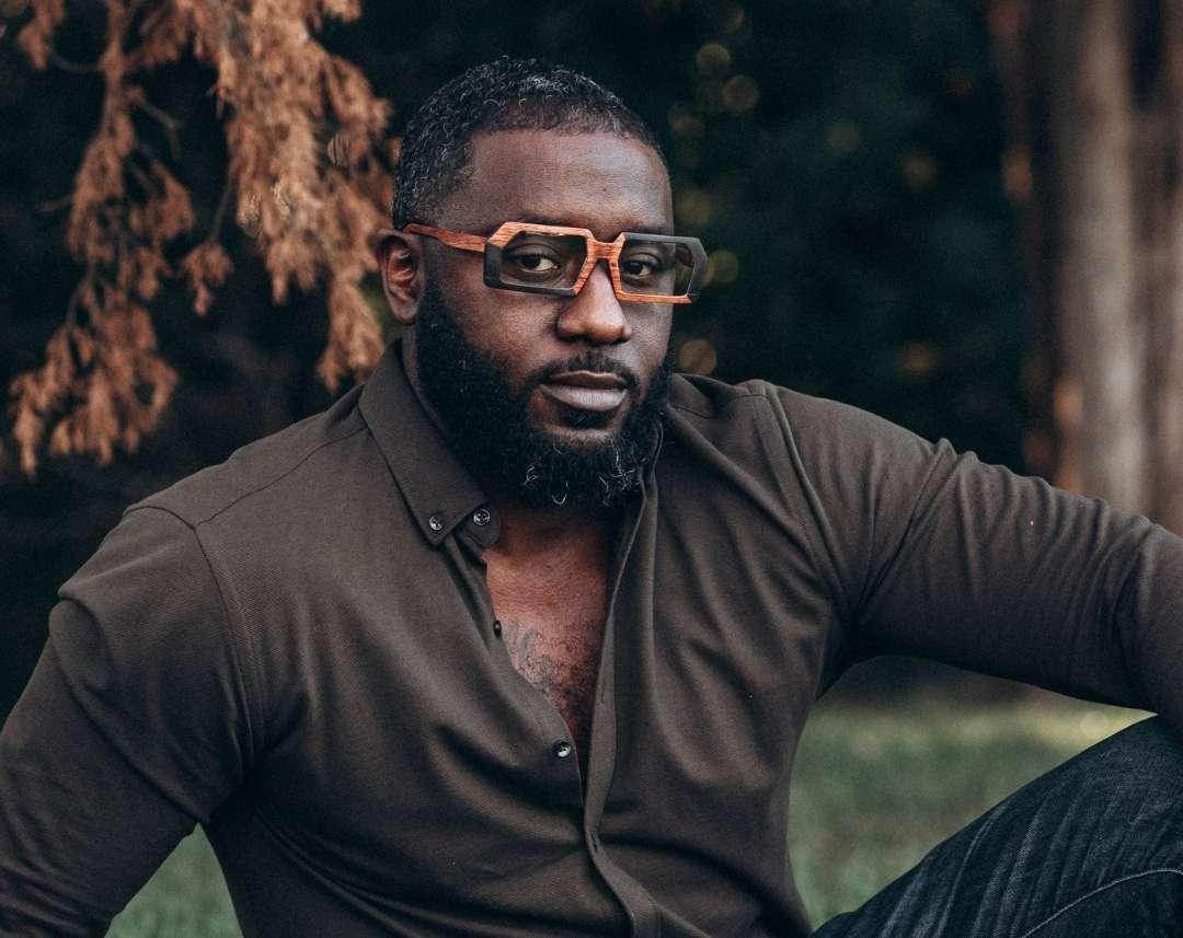 Black man with beard wearing brown and black rectangular wooden glasses made of black birch and brown kevazingo wood by NURILENS.