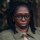 Black woman with short dreadlocks wearing round wooden glasses made of ebony with subtle black wood grain by NURILENS.