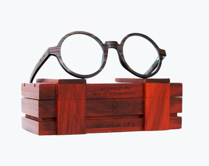 Round brown wooden glasses made of ebony with subtle black wood grain sitting on rosewood wooden case by NURILENS.
