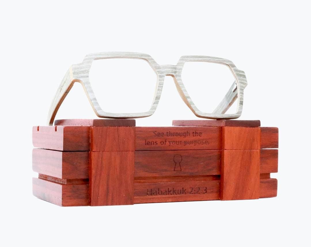 Gray wayframe wooden eyeglasses made of silver oak with subtle black wood grain accents sitting on rosewood wooden case by NURILENS.