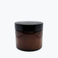 2 ounce brown glass container of Beeswax and Mineral Oil Wood Polish sitting on brown wood polishing cloth by NURILENS.